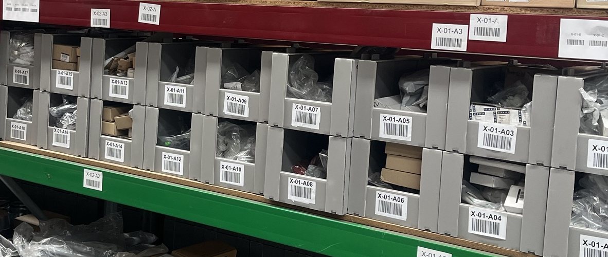 Rows of barcoded grey pick bins on racking inside the Satellite3PL warehouse, Māngere